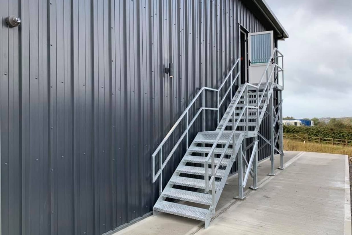 Metal staircase leading to an entrance on the side of a building with a gray exterior.